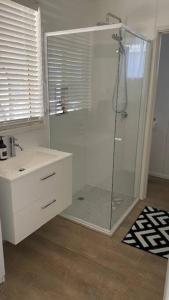 La salle de bains est pourvue d'une cabine de douche en verre. dans l'établissement Rosebud Beach Cottage, à Rosebud