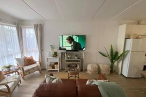 a living room with a couch and a flat screen tv at Rosebud Beach Cottage in Rosebud