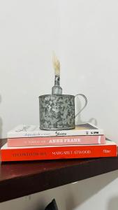 a stack of books sitting on a shelf with a tea pot at Quarto Sertão no Mar in Barra do Cunhau