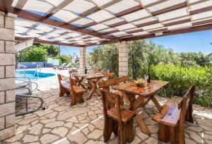 un patio con mesas y sillas de madera y una piscina en Apartment in Prizba - Insel Korcula 6404, en Prizba
