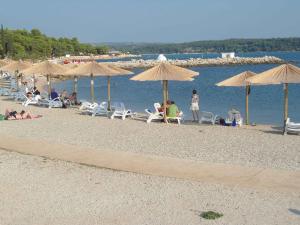 eine Gruppe von Menschen, die am Strand mit Sonnenschirmen sitzen in der Unterkunft Apartment in Novigrad/Istrien 9509 in Novigrad Istria