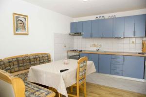 uma cozinha com armários azuis e uma mesa e cadeiras em Apartments in Novi Vinodolski 15349 em Novi Vinodolski