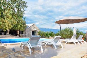 een groep stoelen en een parasol naast een zwembad bij Holiday home in Pucisca/Insel Brac 6050 in Pučišća