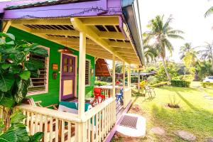 une maison verte dotée d'une terrasse couverte avec des chaises. dans l'établissement Heimanarii,slodge Mahana, à Haapiti