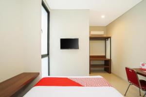a bedroom with a bed and a tv on a wall at The Colins Hotel in Surabaya