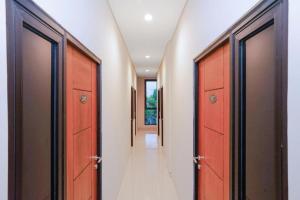 a hallway with orange doors and white walls at The Colins Hotel in Surabaya