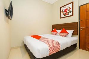 una camera da letto con un letto con cuscini rossi e bianchi di The Colins Hotel a Surabaya
