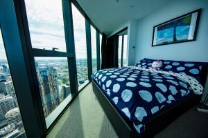 a bedroom with a bed in a room with large windows at New Year eve’s Fireworks & BayView Apt in CBD in Melbourne