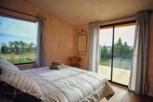 een slaapkamer met een bed en een groot raam bij Casa Las Golondrinas in Cobquecura