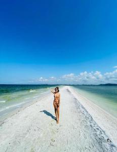 Una donna in bikini che cammina sulla spiaggia di Pousada Arraial do Cabo - Praia dos Anjos ad Arraial do Cabo