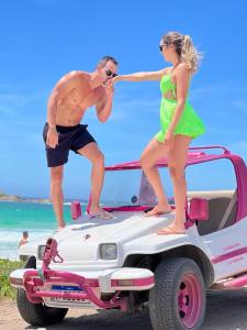 Un uomo e una donna in piedi sul retro di un'auto di Pousada Arraial do Cabo - Praia dos Anjos ad Arraial do Cabo