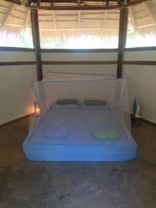 Cama azul en habitación con ventana en Little Nomads eco-guesthouse en Siquijor