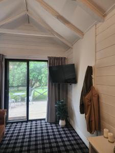 sala de estar con TV de pantalla plana en la pared en Daylesford - Frog Hollow Estate -THE COTTAGE - enjoy a relaxing and romantic night away in our gorgeous little one Bedroom ROMANTIC COTTAGE under the apple tree with water views, en Daylesford