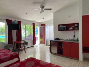 梅里達的住宿－Suites del Sureste - Mérida，一间带一张床的客厅和一间带红色橱柜的厨房