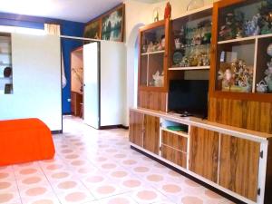 uma sala de estar com televisão e armários de madeira em Belle Maison F3 em Papeete