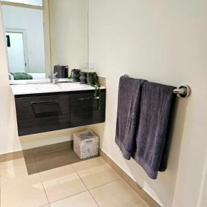 a bathroom with a sink and a mirror and purple towels at Cobb & CoHouse -Luxury Large Home BendigoCBD in Bendigo