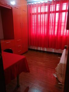 um quarto vermelho com cortinas vermelhas e pisos em madeira em Ruiz Domicile em Kawit