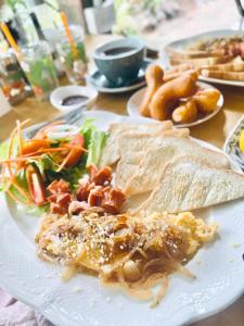 um prato branco coberto com comida numa mesa em กมุทมาศ สวรรคโลก em Ban Pa Muang (1)