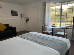 1 dormitorio con cama, mesa y ventana en Port Campbell Motor Inn, en Port Campbell