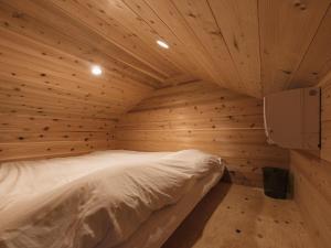 a bedroom with a bed in a wooden room at HATAYA Cafe&Hostel in Kyotango