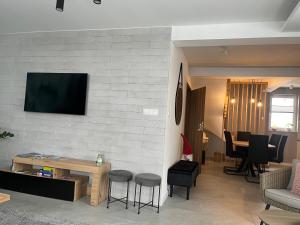 a living room with a table and a tv on a wall at Domek nad stawem in Krynica Zdrój