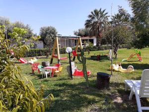 einen Park mit einem Spielplatz mit Stühlen und einer Schaukel in der Unterkunft Apartments Capo Vaticano/Kalabrien 21016 in Ricadi