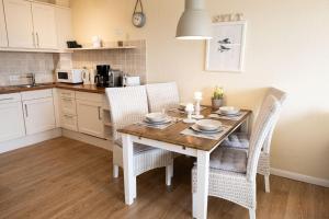 eine Küche mit einem Holztisch mit Stühlen und einem Esszimmer in der Unterkunft Norderhoog 2.OG / O Wohnung 45 in Westerland