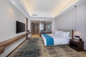 um quarto de hotel com uma cama e uma televisão de ecrã plano em Fortune Land Shenzhen em Shenzhen