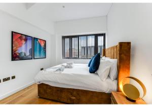 1 dormitorio con 1 cama con sábanas blancas y almohadas azules en Stylish Flat in Centre Hassle Free Peaceful, en Maidenhead