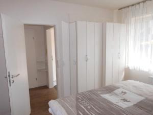 ein Schlafzimmer mit weißen Wänden, einem Bett und einem Fenster in der Unterkunft Ferienwohnung ADL/1 1 in Sankt Peter-Ording