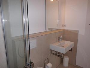 ein Bad mit einem Waschbecken und einer Dusche mit einem Spiegel in der Unterkunft Ferienwohnung ADL/1 1 in Sankt Peter-Ording