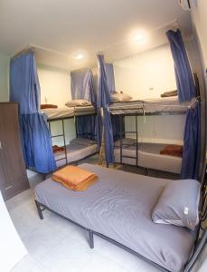a room with three bunk beds with blue drapes at The Travelers Friend En Suite dorm room AC in Ban Ai Dao