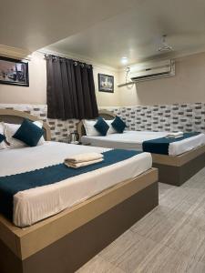 duas camas num quarto de hotel com almofadas azuis em Hotel Vinayak em Kharagpur