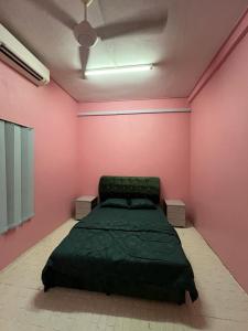 ein Schlafzimmer mit einem grünen Bett in einer rosa Wand in der Unterkunft HOMESTAY Kg TOKKU KOTA JEMBAL in Kota Bharu