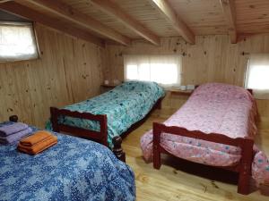 une chambre avec trois lits dans une cabine dans l'établissement Eco del Cielo Apart (Cabaña con patio en 2 plantas para 4), à Villa Pehuenia