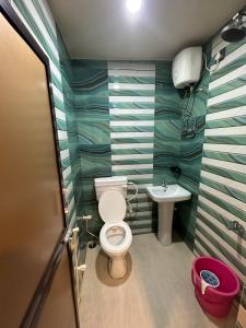 La salle de bains est pourvue de toilettes et d'un lavabo. dans l'établissement Hotel Vinayak, à Kharagpur