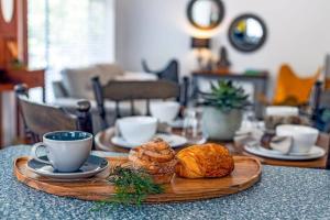 una mesa con un plato de bollería y una taza de café en LUXMI - "New to Booking", en Katoomba