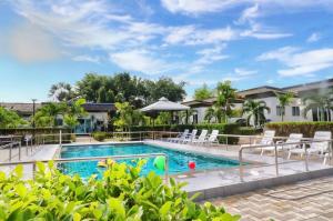 une piscine dans un complexe avec des chaises blanches et des arbres dans l'établissement Billabong Golf Club & Resort, à Nong Prue