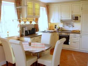 eine Küche mit weißen Schränken sowie einem Tisch und Stühlen in der Unterkunft  Mare Frisicum 2 in Sankt Peter-Ording