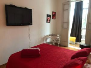 a bedroom with a red bed with a flat screen tv on the wall at Aconchegante Lapa in Rio de Janeiro