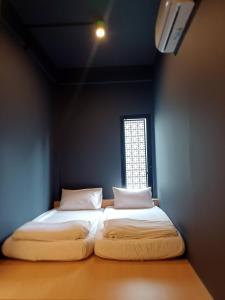 2 Betten in einem Zimmer mit Fenster in der Unterkunft CLOUD on Saladaeng Silom Hostel Bangkok in Bangkok