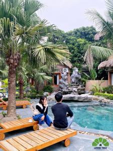 um homem e uma mulher sentados num banco junto a uma piscina em Lemon Tree Homestay Tam Coc em Ninh Binh