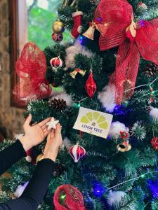 Una mujer decorando un árbol de Navidad con arcos rojos en Lemon Tree Homestay Tam Coc en Ninh Binh