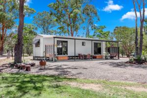 a white tiny house in a park with trees at Little Sunshine - Private acreage Guest Home in Hervey Bay