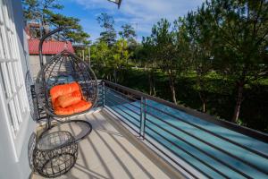 a swing on a balcony with an orange pillow at Suri Homestay in Da Lat