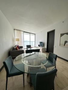 uma sala de estar com uma mesa de vidro e cadeiras em Apartamento 5 estrellas, vista al mar na Cidade do Panamá