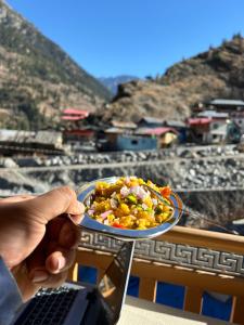 a person holding a plate of food with a laptop at Laxmi Narayan Homestay-Harshil in Harsil