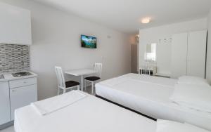 Habitación blanca con 2 camas y mesa en Apartments Villa Luce, en Neum