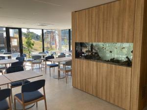 a restaurant with tables and chairs and a fish tank at Solasuna in Yukuhashi