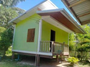 a small green house with a balcony on top at Sukanyawoodhouse in Ban Tha Rua